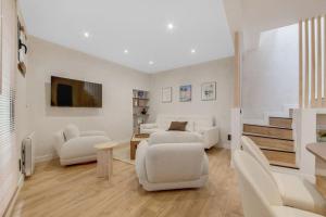 a living room with white furniture and a tv at Luxueuse maisonnette au coeur de Batignolles 17eme in Paris