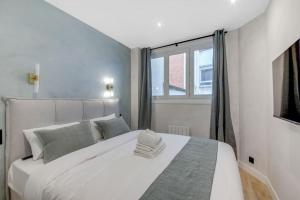 a white bed in a room with a window at Luxueuse maisonnette au coeur de Batignolles 17eme in Paris