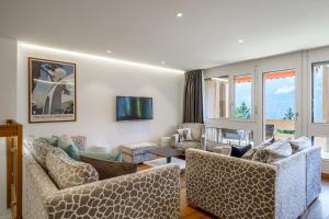 a living room with couches and chairs and windows at Chalet Veronica in Wengen