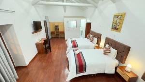Un dormitorio con dos camas y una sala de estar. en Casona Libertrek Inn, en Cusco