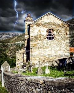 Une ancienne église avec foudre dans le ciel dans l'établissement Nuits magiques au village entre mer et montagnes, à Bigorno