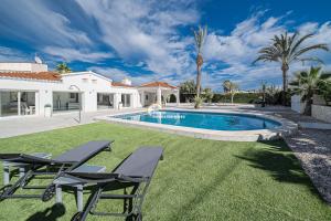 einen Hinterhof mit Pool und 2 Stühlen in der Unterkunft Villa Pyeranch in Torrevieja