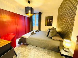 une chambre avec un grand lit et un mur rouge dans l'établissement La Suite Shelby, T3 hypercentre, à Beauvais