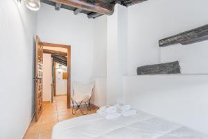 a white bedroom with a bed and a chair at CASA RURAL EL GARROTE in Gea de Albarracín