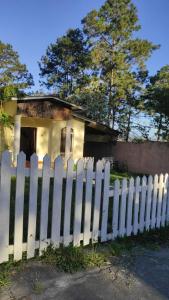 a white picket fence in front of a small house at La casa de la Gaviota in Siguatepeque