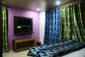 - une chambre avec un lit, une télévision et des rideaux dans l'établissement Plaza HomeStay, à Mussoorie