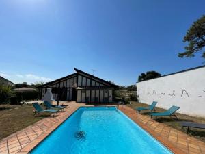 a swimming pool with chairs and a building at Villa Labenne, 5 pièces, 8 personnes - FR-1-413-227 in Labenne