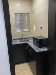 a kitchen with a sink and a microwave on a counter at Hope Residence hotel and suite in Lagos