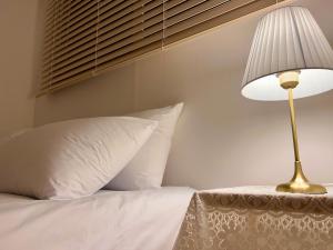 a lamp sitting next to a bed with white pillows at DOBOY House in Seoul