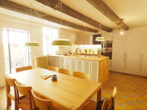 eine große Küche mit einem Holztisch und Stühlen in der Unterkunft L’IMPASSE DES BATELIERS- magnifique maison pour 7 in Arles