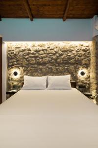 ein Schlafzimmer mit einem weißen Bett und einer Steinmauer in der Unterkunft Πέτρινη Αγροικία 2 Stone Manor 2 in Kastraki