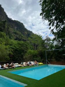 un grupo de personas sentadas alrededor de una piscina en Mountain View Party Hostel, en Ban Chong Phli