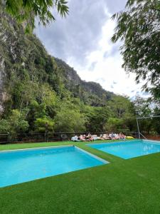 a swimming pool with people laying on the grass at Mountain View Party Hostel in Ban Chong Phli