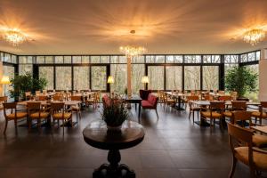 un comedor con mesas, sillas y ventanas en STEIGER Parkhotel Hohnstein, en Bad Schandau