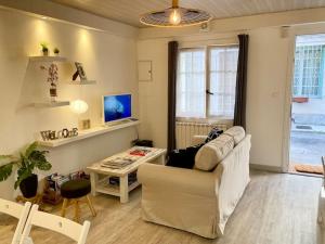 een woonkamer met een bank en een tafel bij Rare Maison au centre ville avec terrasse et clim Arles Camargue in Arles