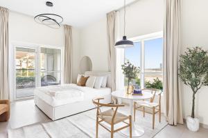 a white living room with a bed and a table at Silkhaus Sea View studio in Marina Rise Tower in Abu Dhabi