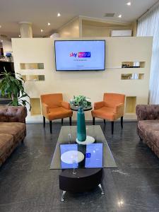 a lobby with a waiting room with chairs and a tv at iH Hotels Milano Blu Visconti in Trezzano sul Naviglio