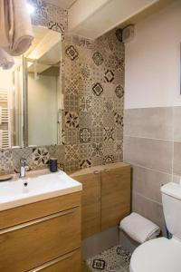 een badkamer met een wastafel, een toilet en een spiegel bij Rare Maison au centre ville avec terrasse et clim Arles Camargue in Arles