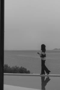 una persona caminando en una cornisa mirando hacia el océano en LASPI / PETRES, en Pefkali