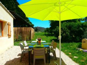 uma mesa com um guarda-chuva amarelo num quintal em La petite Palasse em Le Thor