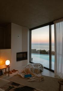 una camera da letto con una grande finestra con vista sull'oceano di LASPI / PETRES a Pefkali