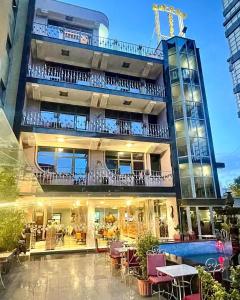 un edificio con balcón con mesas y sillas en Hotel Elysee, en Tirana
