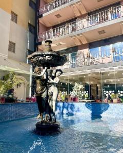 una estatua de una pareja bajo un paraguas en una fuente en Hotel Elysee, en Tirana