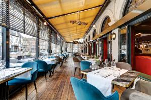 a restaurant with tables and blue chairs and windows at Hotel Brasserie Den Engel in Baarle-Nassau