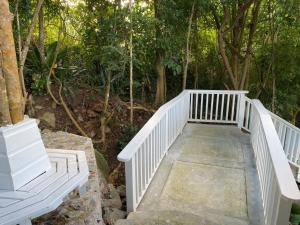 un pont en bois blanc avec deux bancs dans une forêt dans l'établissement SummervilleBVI, à Great Mountain