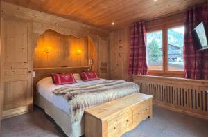 Un dormitorio con una cama con almohadas rojas y una ventana en La Clef des Champs en Morzine