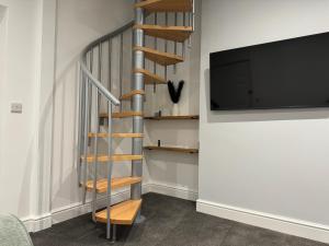 a spiral staircase in a room with a flat screen tv at Broadway Terrace with Hot tub in Kent