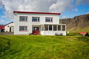 a white house with a red door on a green field at Vagnsstadir in Borgarhöfn