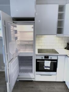cocina blanca con nevera abierta y horno en The Apartments Company - Bislett, en Oslo