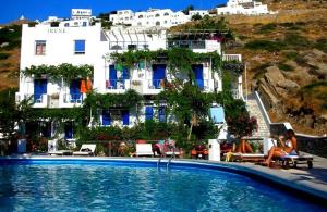 a woman sitting next to a swimming pool in front of a building at Pension Irene in Ios Chora +16 photos