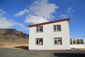 a white building with a mountain in the background at Vagnsstadir in Borgarhöfn