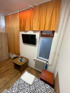 um pequeno quarto com uma cama e uma televisão em Álom Vendèghàz em Dunaújváros