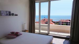 Un dormitorio con una cama y vista a un balcón. en High in the Sky Apartments, en Sozopol
