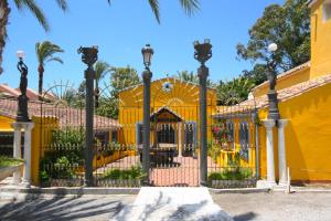 マルベーリャにあるCortijo La Saleta Banúsのヤシの木と遊び場のある黄色い門