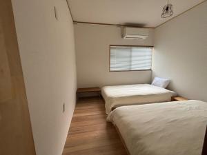 a small room with two beds and a window at Hostel Mt. Fuji - FUKUYA in Fujiyoshida
