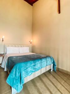 um quarto com uma cama com um cobertor azul em Chalés Belo Vale - Tiradentes em Tiradentes