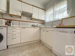 a kitchen with white cabinets and a washer and dryer at La Bella Lola Estartit Rental in L'Estartit