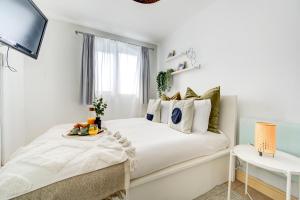 biała sypialnia z łóżkiem i oknem w obiekcie BOHO Chic Tower Bridge Gem, Sleeps 8 w Londynie