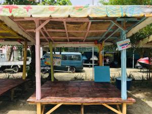 un banco de madera bajo un pabellón en un aparcamiento en The Beach Park Hadsan en Lapu Lapu City