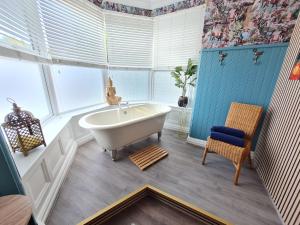 een badkamer met een wit bad en een stoel bij Lemur Lodge - Boutique Apartments - Short Stroll to The Beach in Bournemouth