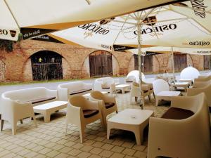 ein Restaurant mit weißen Tischen, Stühlen und Sonnenschirmen in der Unterkunft Hi Hostel Stara Pekara Osijek in Osijek