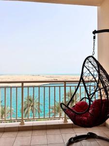 a hammock sitting on a balcony overlooking the ocean at Nazeel - Sea view Marina Apt in King Abdullah Economic City