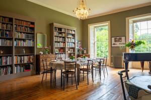 a dining room with a table and chairs and bookshelves at Kilfane Glebe House in Thomastown