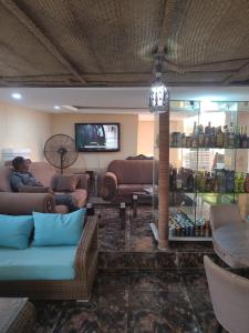 uma sala de estar com sofás, uma televisão e uma mesa em Dazzle Hotels and Apartments Riverpark em Rubuchi