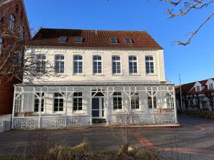 een oud wit gebouw met een rood dak bij Georg6 GEORG6 - Fewo 4 in Norderney