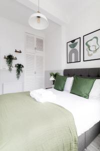 een witte slaapkamer met een groot bed met groene kussens bij Modern Kensington Apartments in Londen